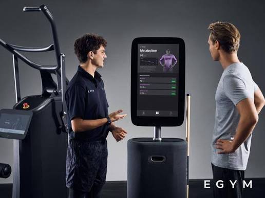 Trainer legt de EGYM Fitness Hub uit aan een klant