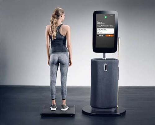 Dame staat op de Seca lichaamsanalyseweegschaal naast de EGYM Fitness Hub